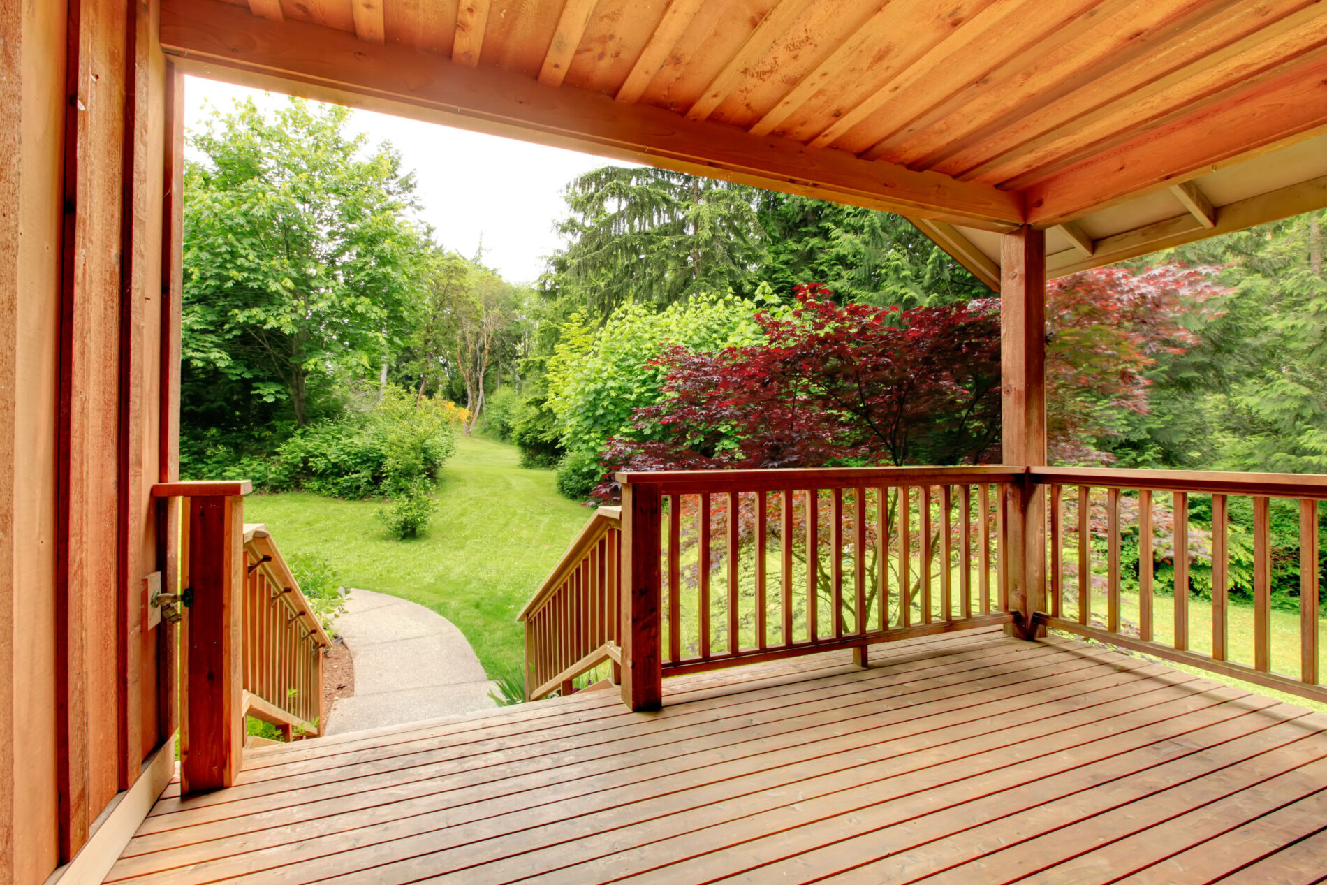 Covered wooden deck overlooking a green backyard